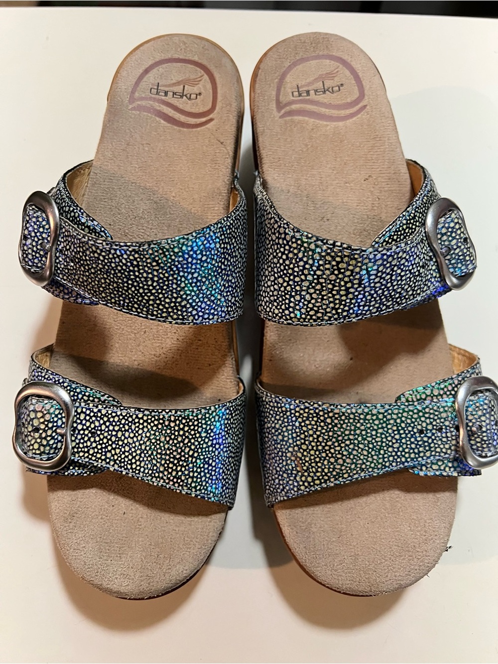 Dansko Sophie slide sandals with iridescent blue-green textured metallic finish.